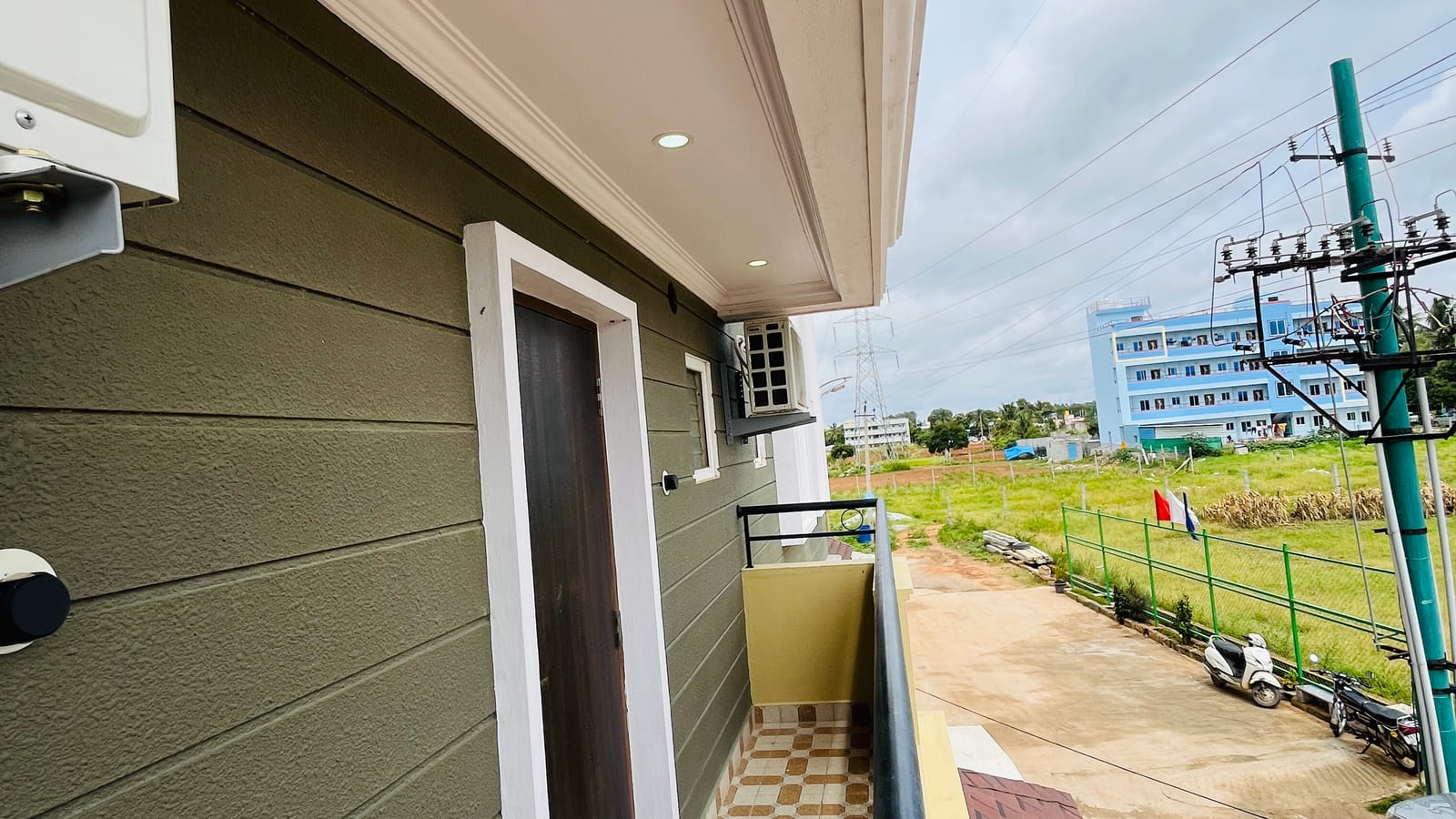 Private balcony of the Standard Balcony Room at Value Inn, Bangalore Airport with chequered flooring and views over open green fields