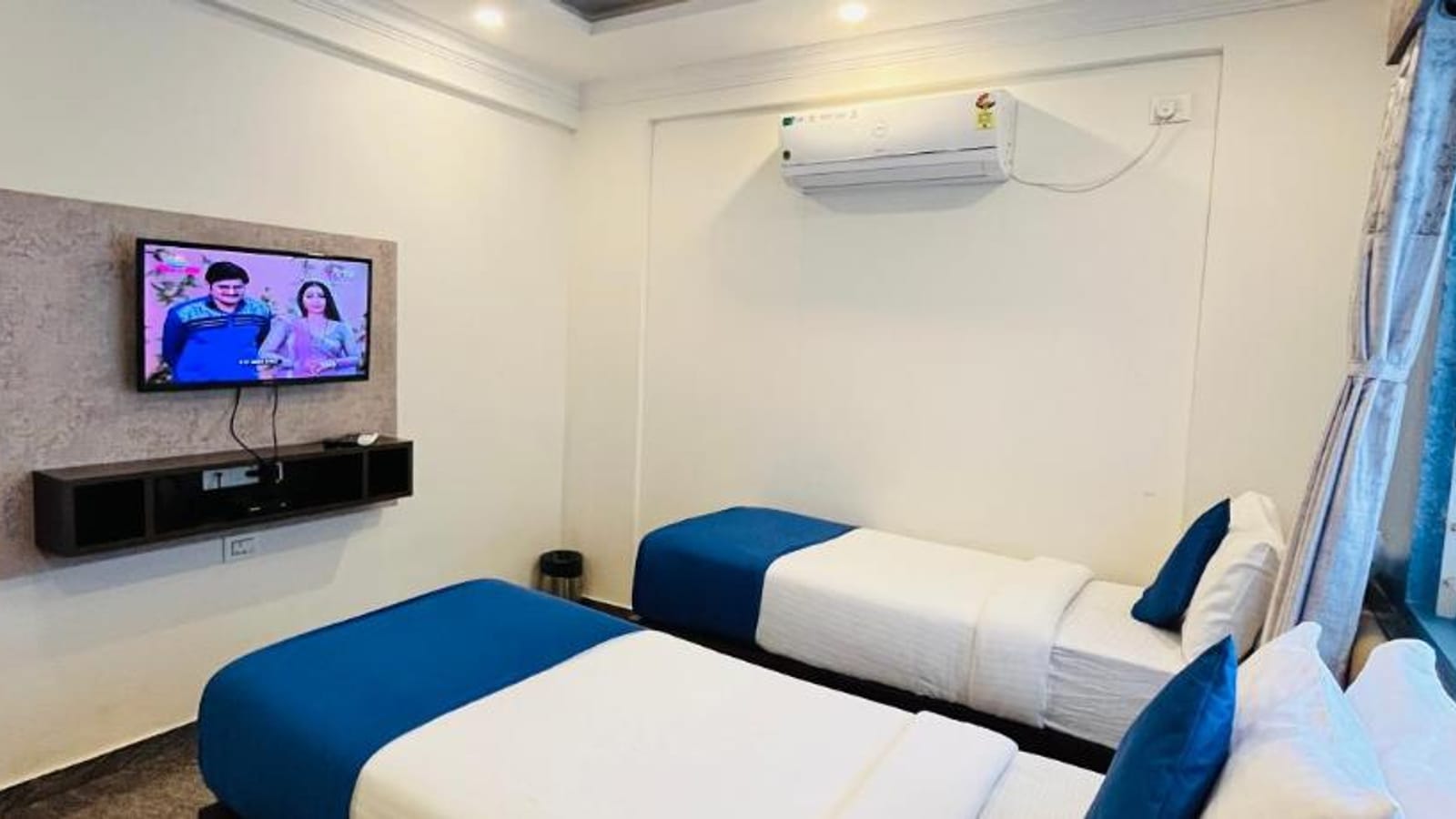 Standard AC Twin Room at Value Inn, Bangalore Airport with a wall mounted TV, an air conditioner, and 2 single beds with blue runners