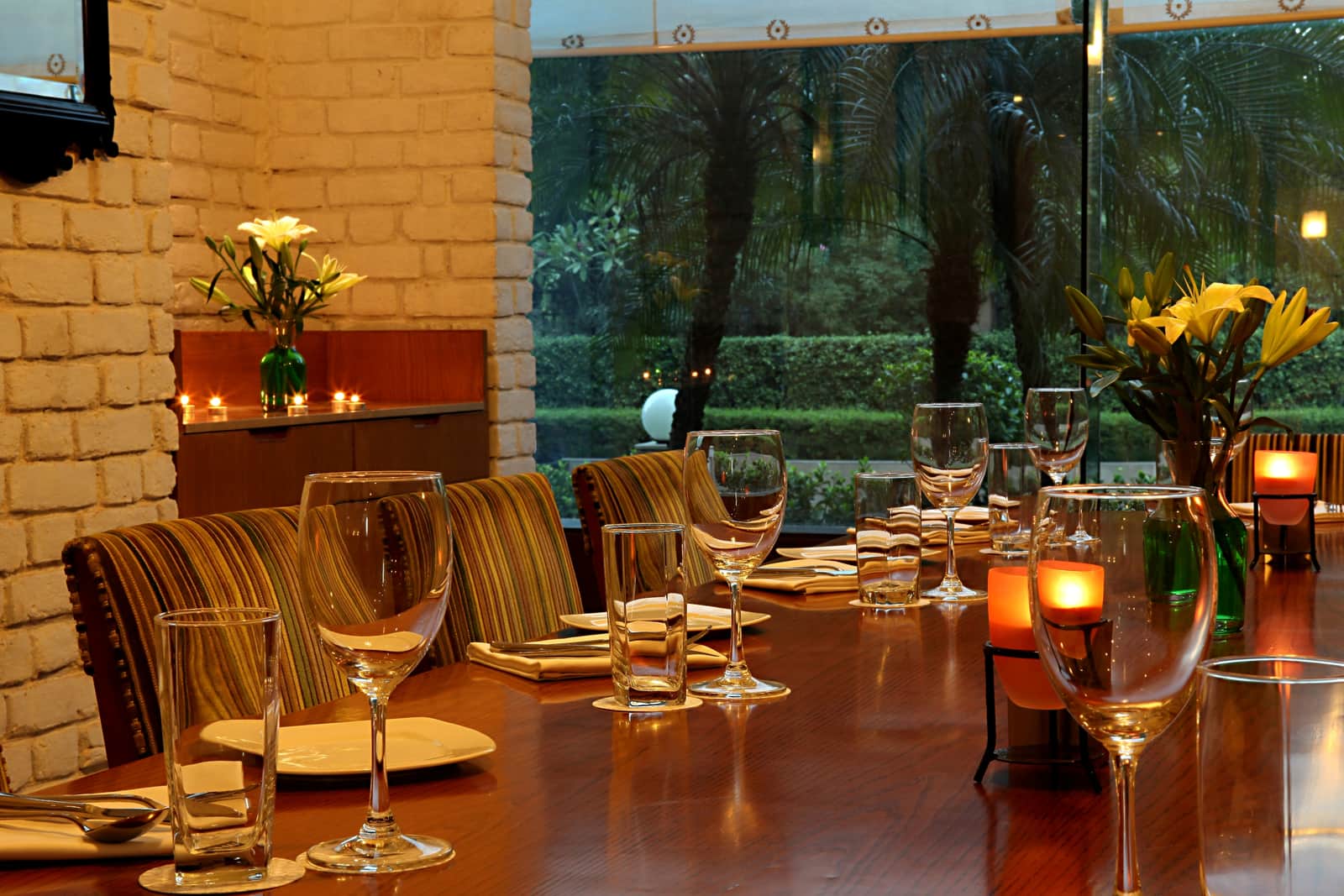 A table laid with glassware beside the garden windows at Chutney