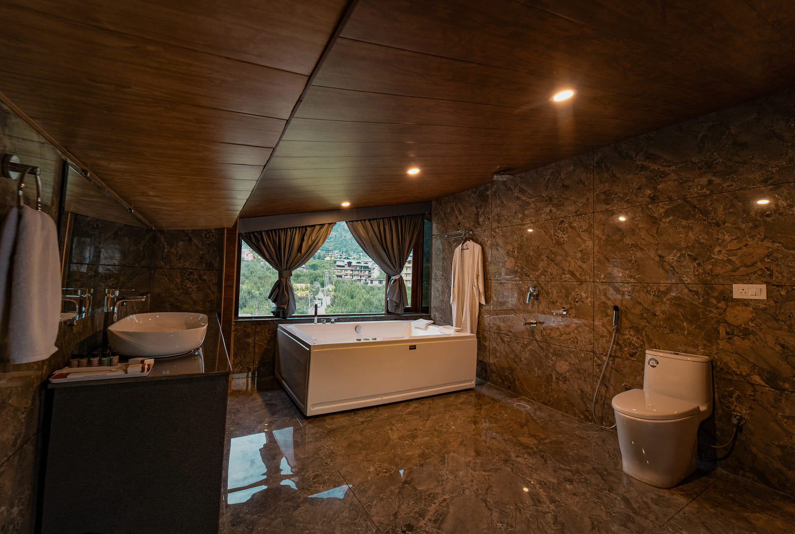Private Jacuzzi tub in the Nazaara Luxe Duplex room, positioned beside a window with a clear mountain view, Manali