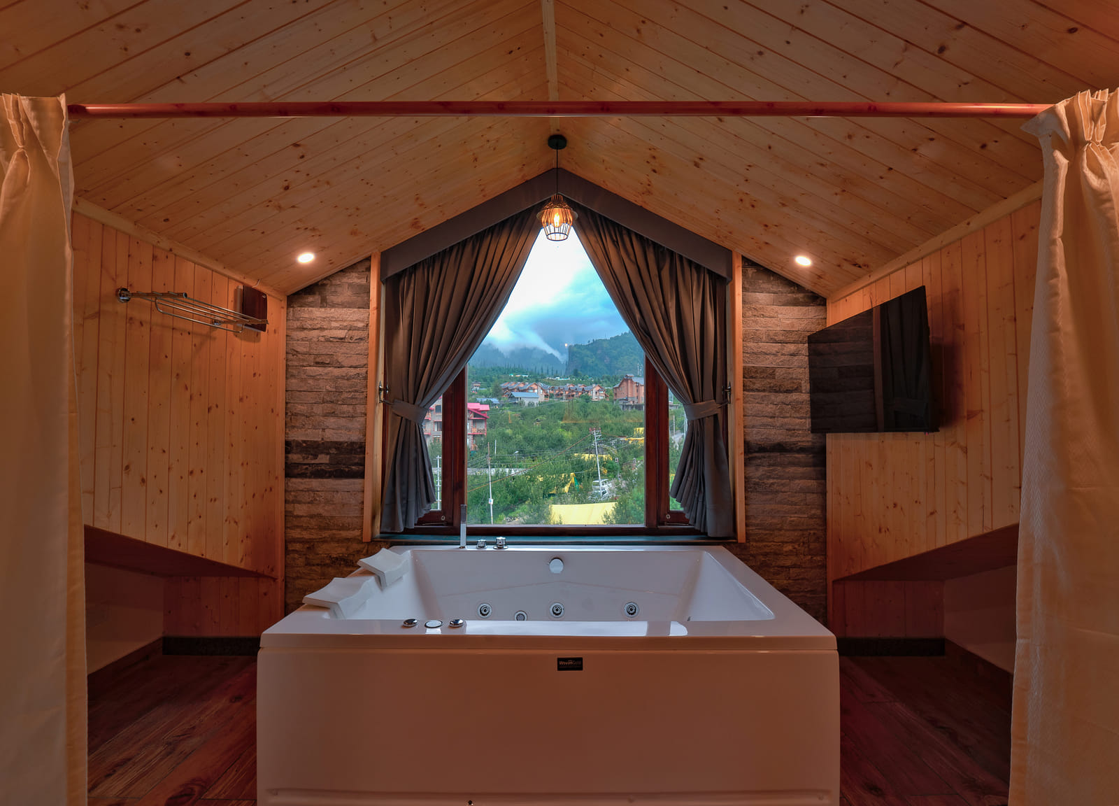 Private Jacuzzi tub beside a window in the Nazaara Luxe room at Nazaara Luxe Retreat, framed by a view of the Manali valley