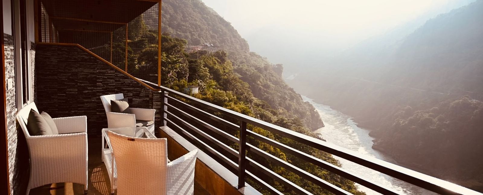 Shot of the mountains and the Ganga from the balcony at the hotel featuring a cosy seating arrangement.| The Tattva Devprayag