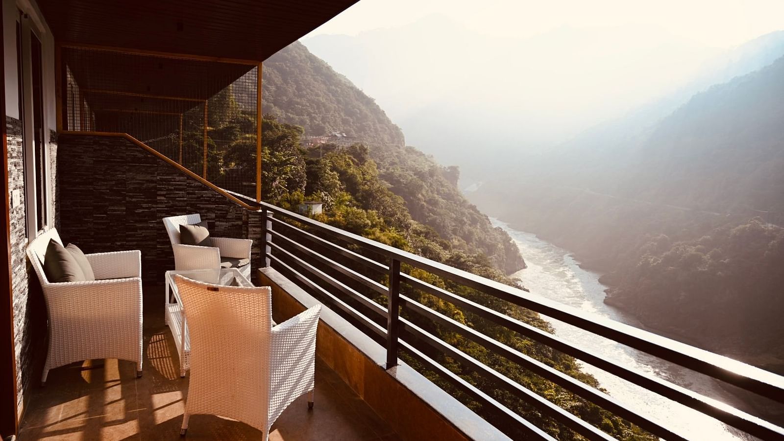 Shot of the mountains and the Ganga from the balcony at the hotel featuring a cosy seating arrangement.| The Tattva Devprayag