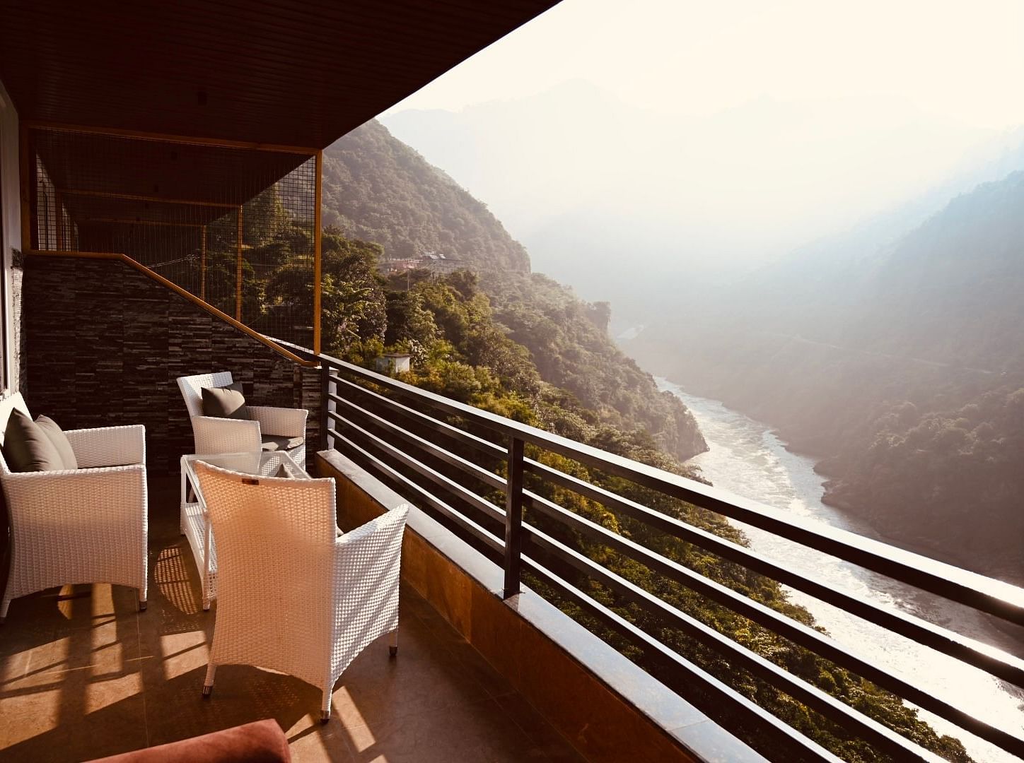 Shot of the mountains and the Ganga from the balcony at the hotel featuring a cosy seating arrangement.| The Tattva Devprayag
