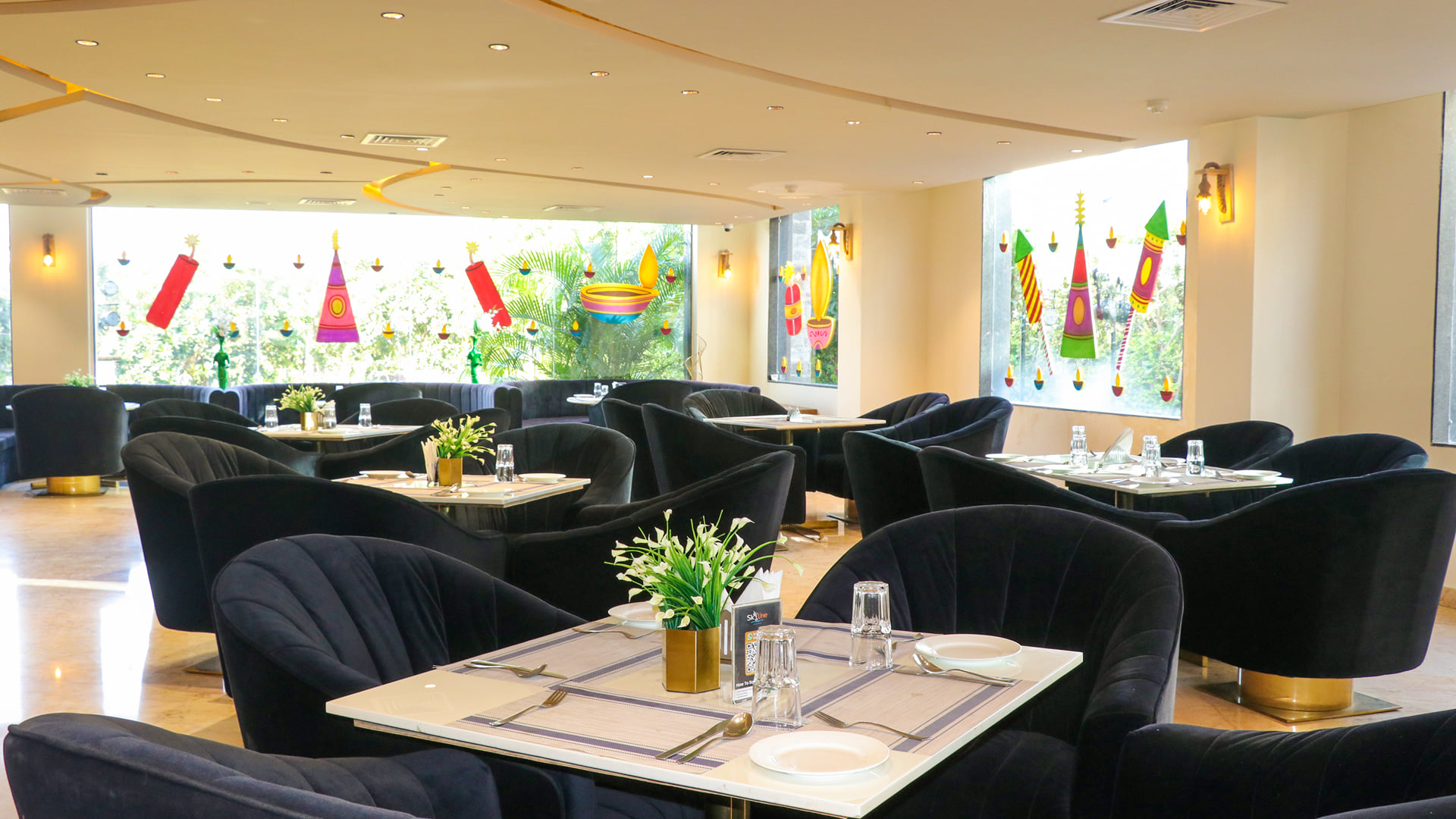 Black velvet tub chairs around set tables beside festive painted glass windows in the Zeus restaurant