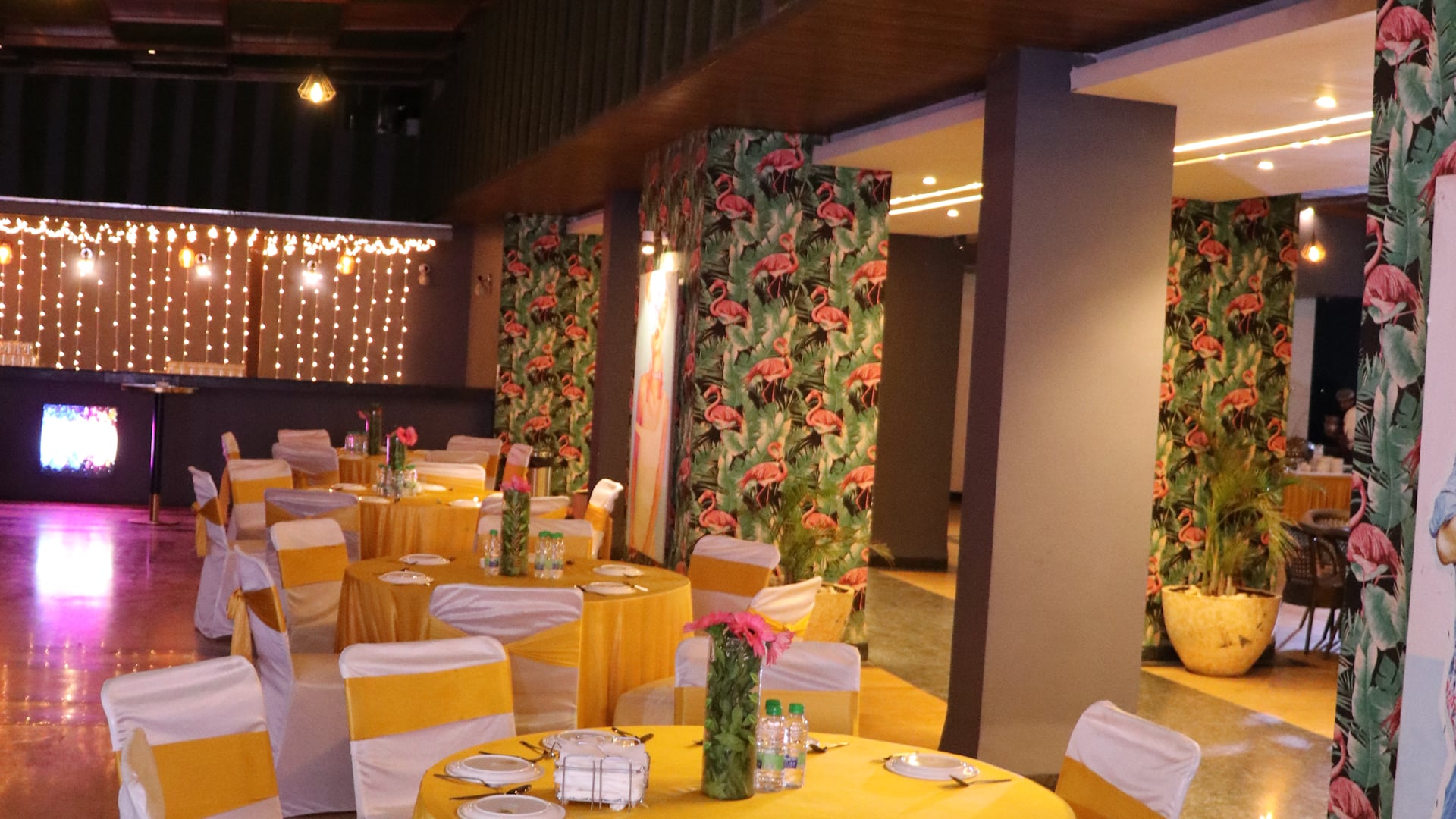 Roof Top venue with round tables in yellow linen, white chair covers and fairy lights
