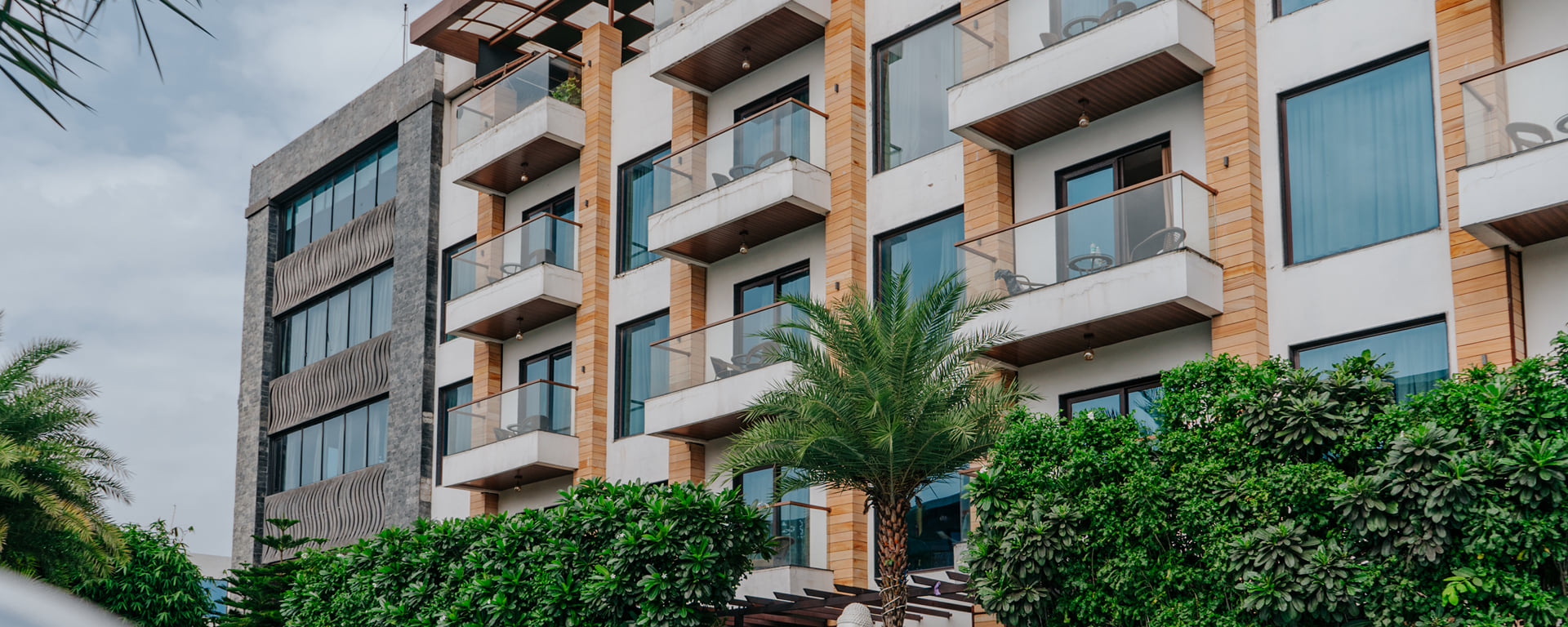 Skyline Resort & Convention Centre building with balconies above palm trees and trimmed hedges in Indore