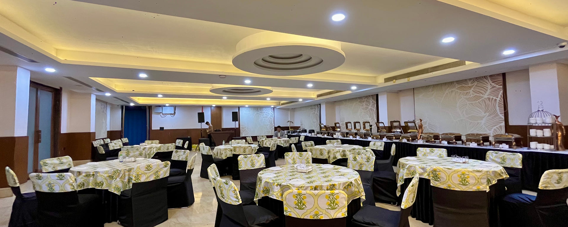 Pearl Hall laid out with round tables in patterned linen and a buffet line under a coved ceiling