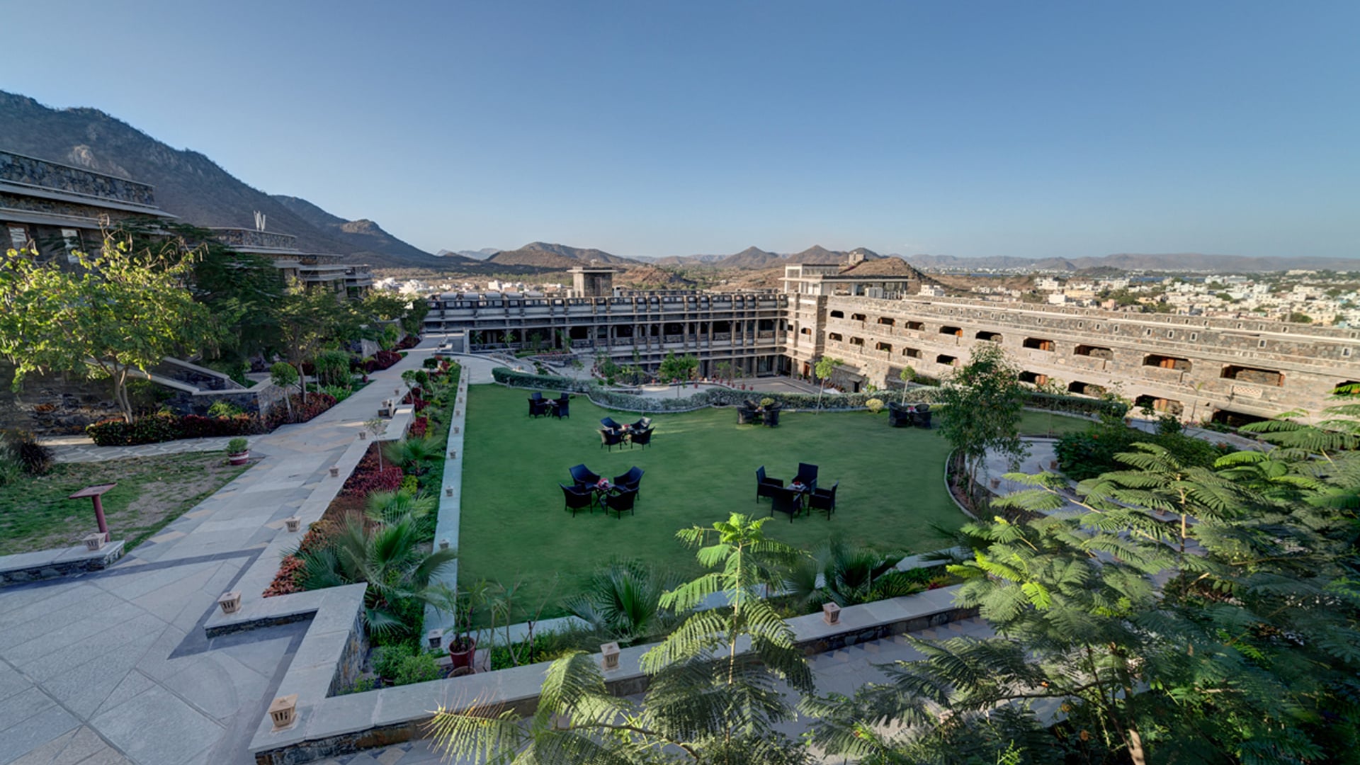 Aerial view of the lawns and stone buildings of Ramada by Wyndham Udaipur Resort and Spa