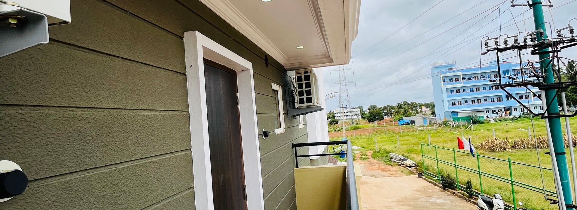 Private balcony of the Standard Balcony Room at Value Inn, Bangalore Airport with chequered flooring and views over open green fields