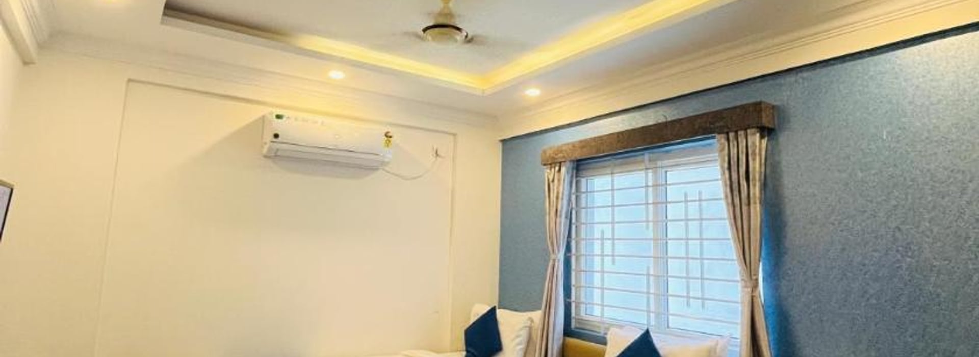 Standard AC Twin Room at Value Inn, Bangalore Airport with 2 single beds, a wall mounted air conditioner, and warm cove ceiling lighting