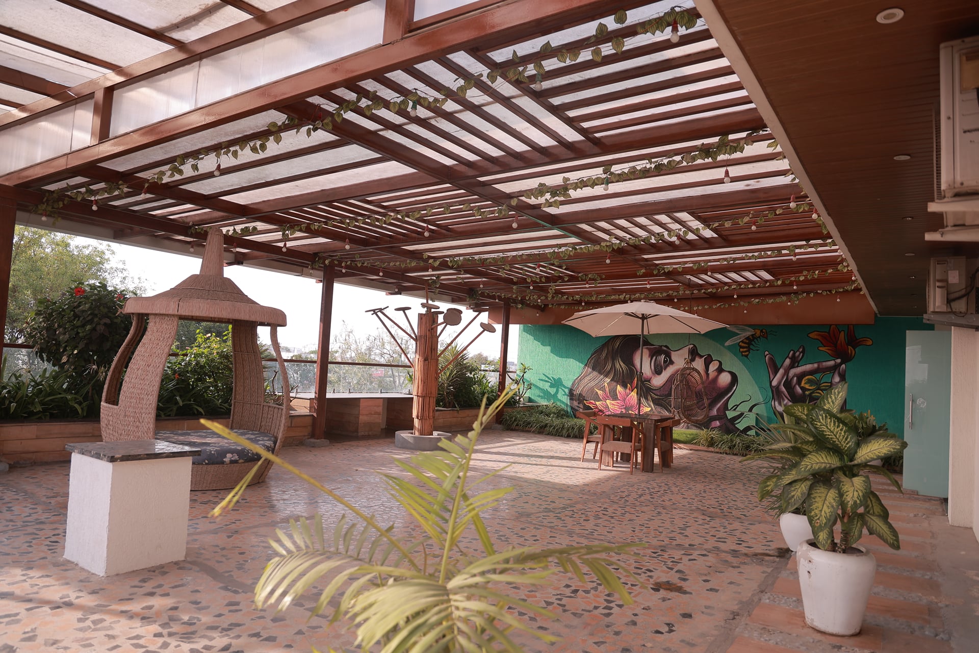 Pergola-covered terrace with potted plants and a colourful painted wall at Skyline by Miraya, Indore