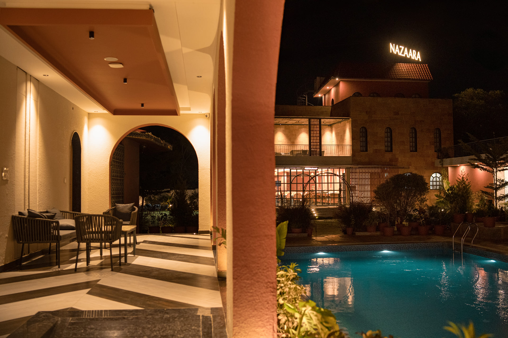 Nazaara Hills Retreat, Udaipur, pool corner framed by a stone pillar with loungers