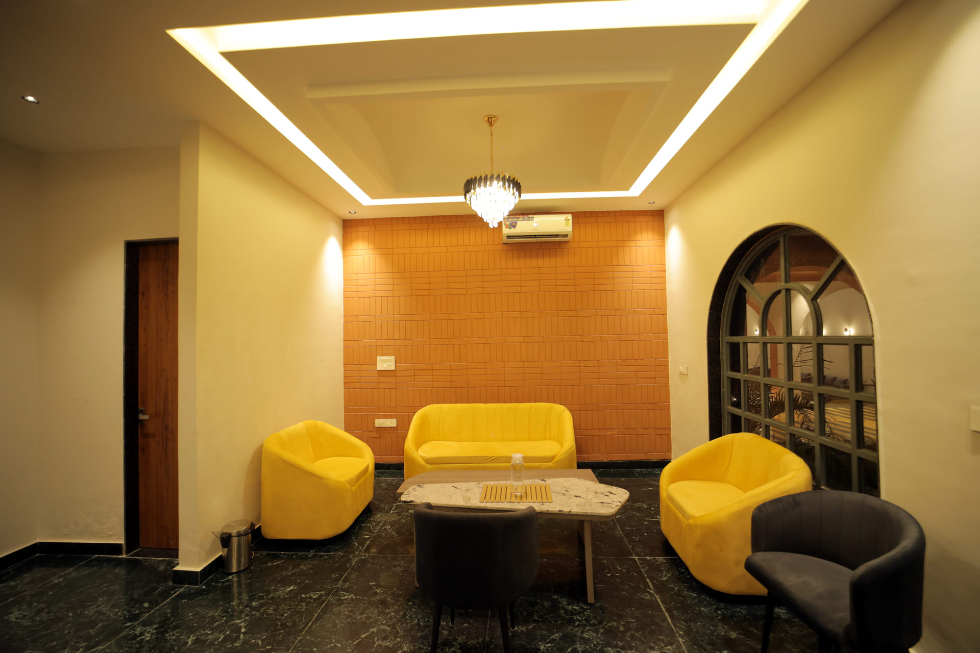 Yellow sofa seating in the reception lounge at Nazaara Hills Retreat, Udaipur, framed by an arched doorway