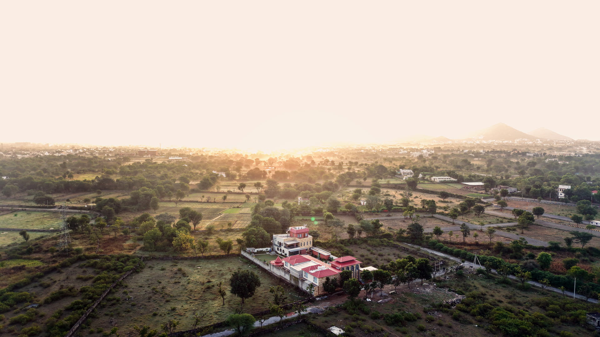 Aerial view of Nazaara Hills Retreat at sunrise, the Aravalli hills stretching beyond, Udaipur