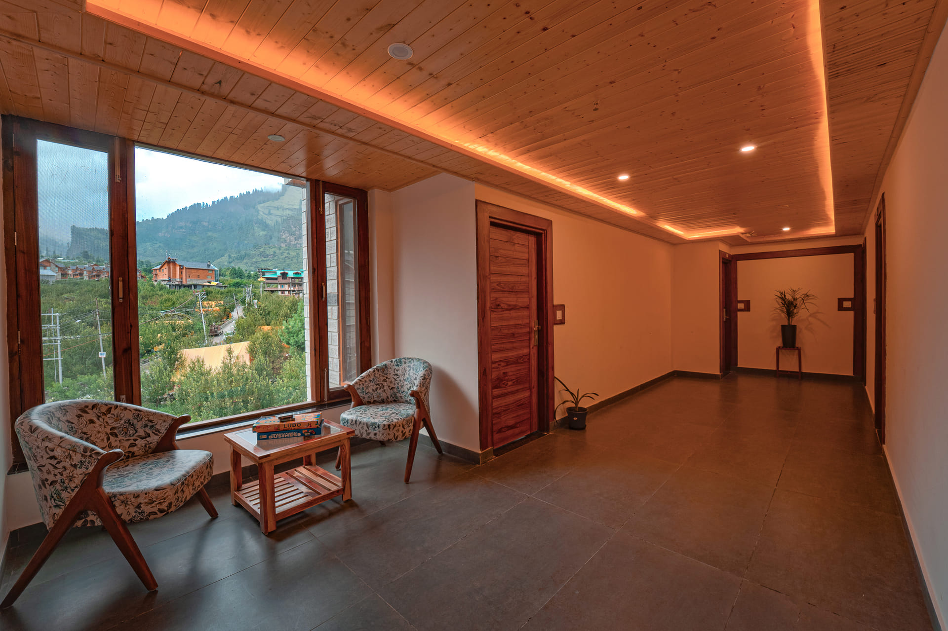 Corridor lounge seating at Nazaara Luxe Retreat looking out over a wide, snow-capped mountain view, Manali