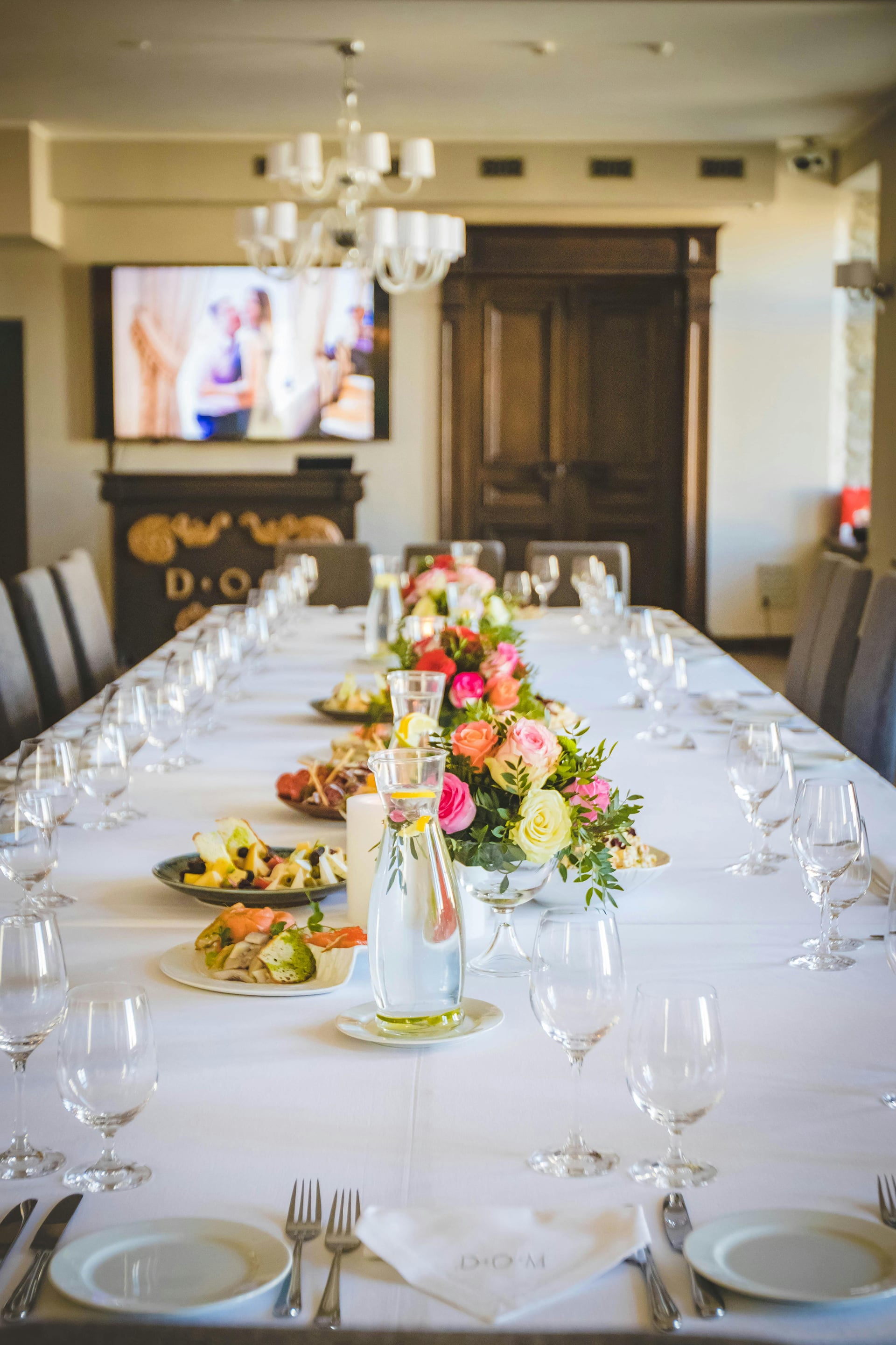 A long table dressed in white linen with pink flowers and place settings, set for a meal at The Garud Forest, Tadoba