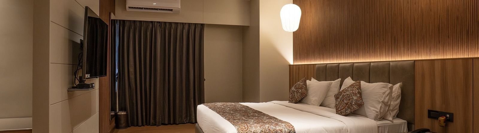 A double bed with a tv in front of it inside super deluxe room - The Cindrella Hotel, Siliguri