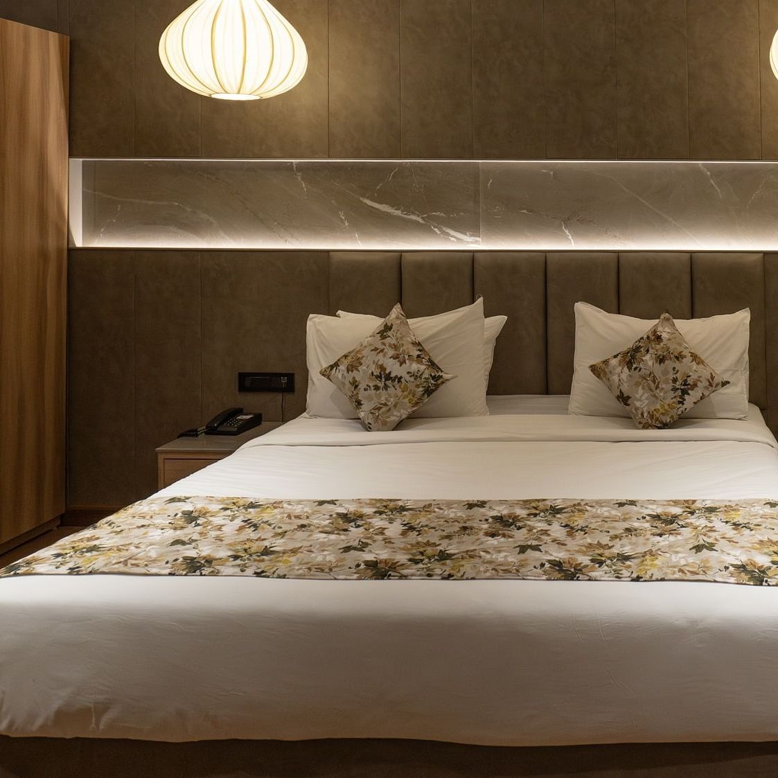 a double bed with lamps above and a wardrobe inside the suite - The Cindrella Hotel, Siliguri