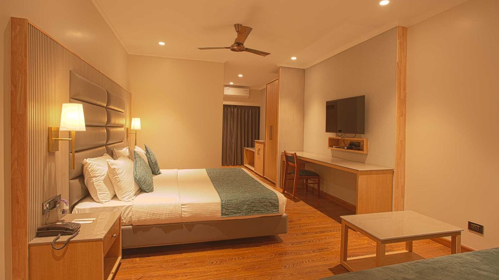 side view of the double bed in front of a tv - Pool view room - The Cindrella Hotel, Siliguri