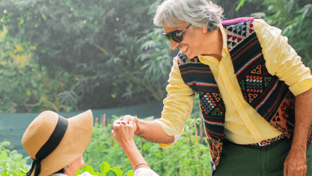 A couple in the garden spending quality time with each other with drinks, fruit baskets, and other food item kept in a table at Karma Chalets.