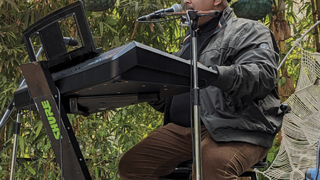 Live music performance by a keyboard artist during an outdoor event at Karma Chalets, set under festive decor amidst lush greenery.