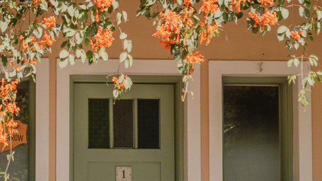 A charming doorway surrounded by vibrant orange blossoms, showcasing the scenic beauty of Karma Chalets.