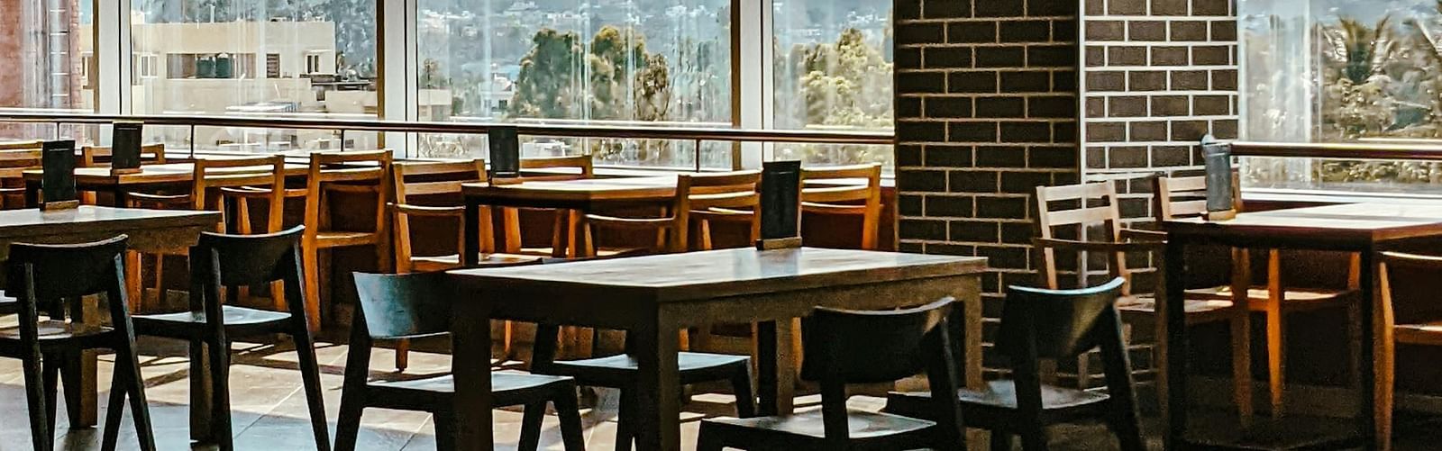 An image of a dining hall with many table and chairs | Inde Hotel Golf Course Extension