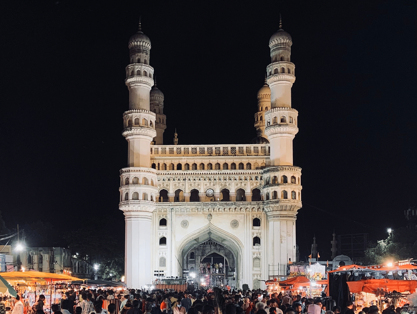 The illuminated Charminar stands against the night sky, drawing visitors to this iconic Hyderabad landmark.