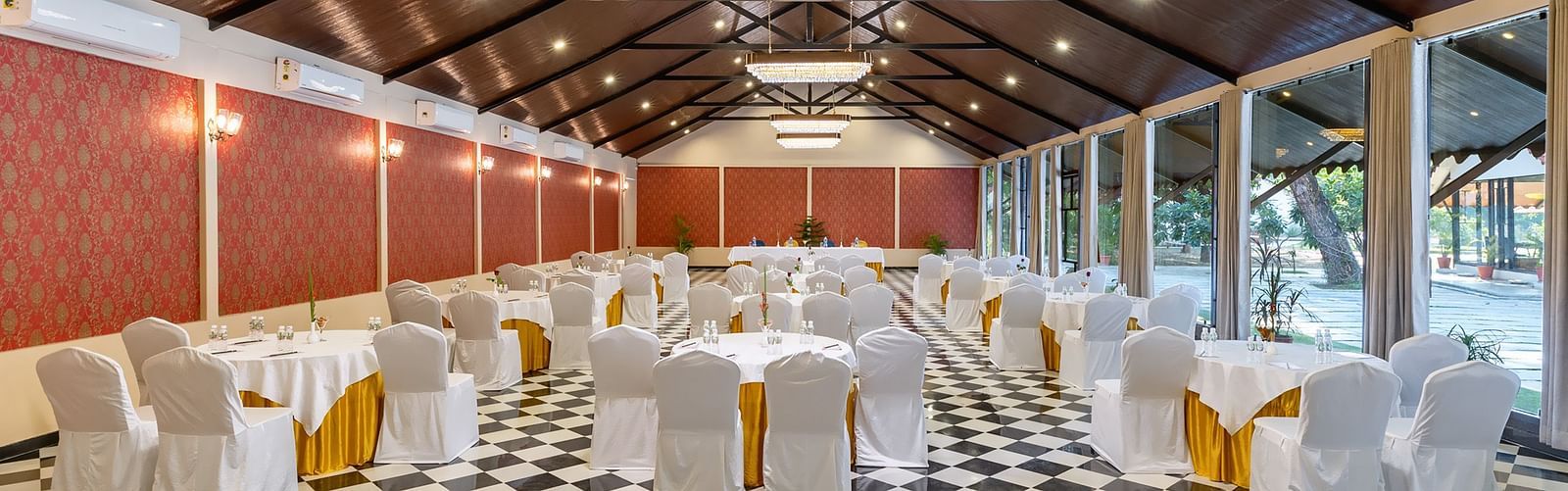 image of an expansive banquet hall with black and white marble flooring with chairs and tables arranged systematically at aranya vilas