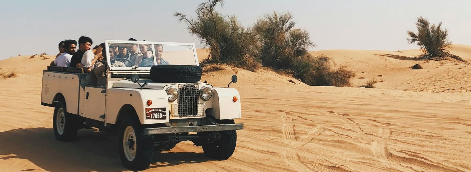 A jeep driving through a sandy desert landscape.