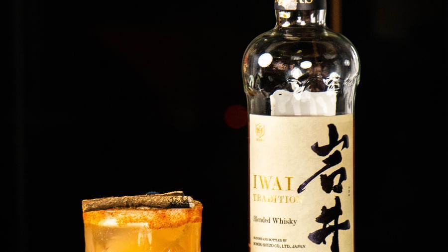 Bottle placed next to a glass filled with a drink on a reflective surface at Asiatic Lounge.