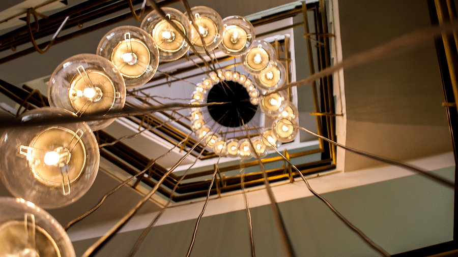 View from below of a spiral staircase with a chandelier of round lights | T24 Retro