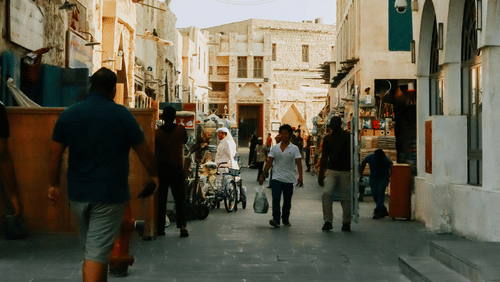 Narrow alleyway in a historic market with people walking past shops.