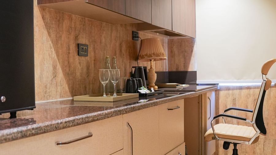 A well-equipped kitchenette at The Meriton, featuring wooden cabinetry, a counter top, and an oven built into the units.