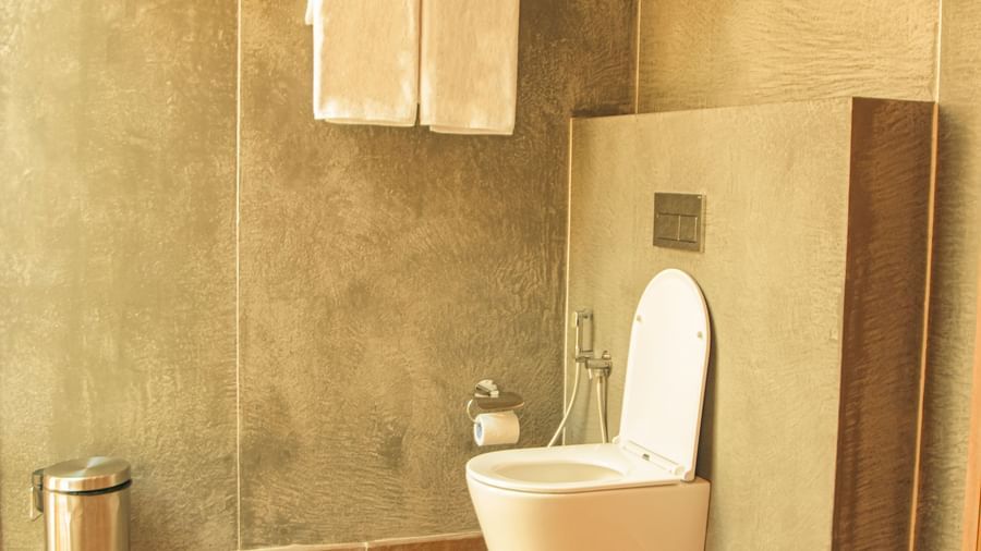 Bathroom with grey walls, toilet and towels at Fireflies Resorts, Kabini.