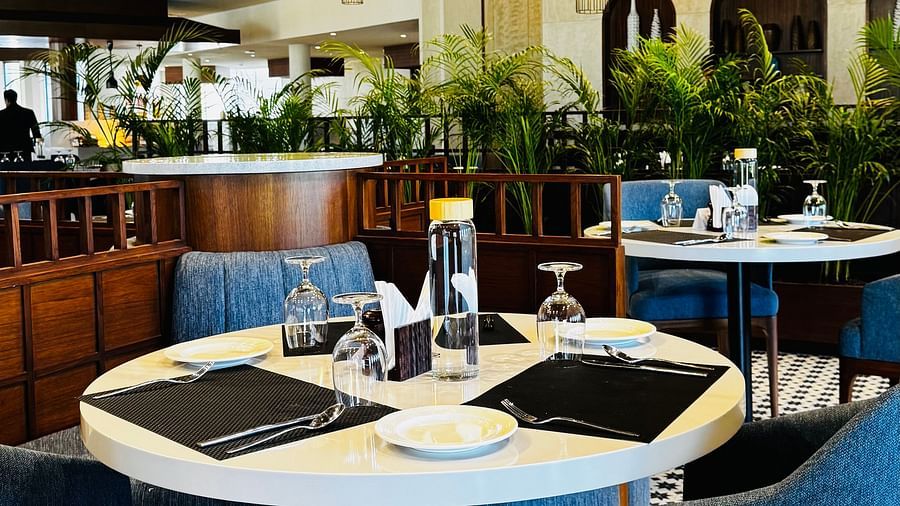 An dining table is set up with blue and white plates under a thatched roof. | Ananta Spa and Resort Ajabgarh