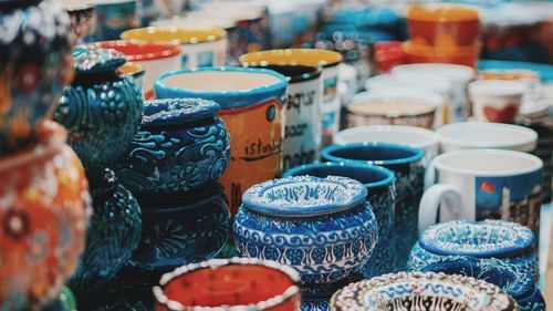 Colourful pots and artefacts displayed at a bustling local handicraft market.