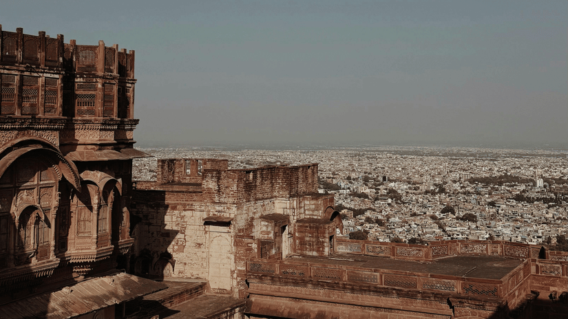 Dark, towering stone walls of a historical fort rise sharply against a clear, pale sky in a vertical composition.