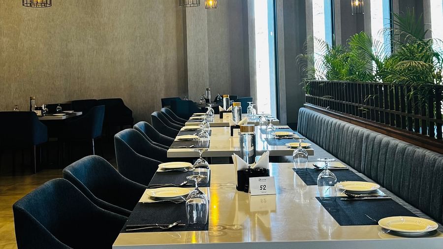 A long dining table with a white cloth and chairs is under a thatched roof with lamps. |  Ananta Spa and Resort Ajabgarh