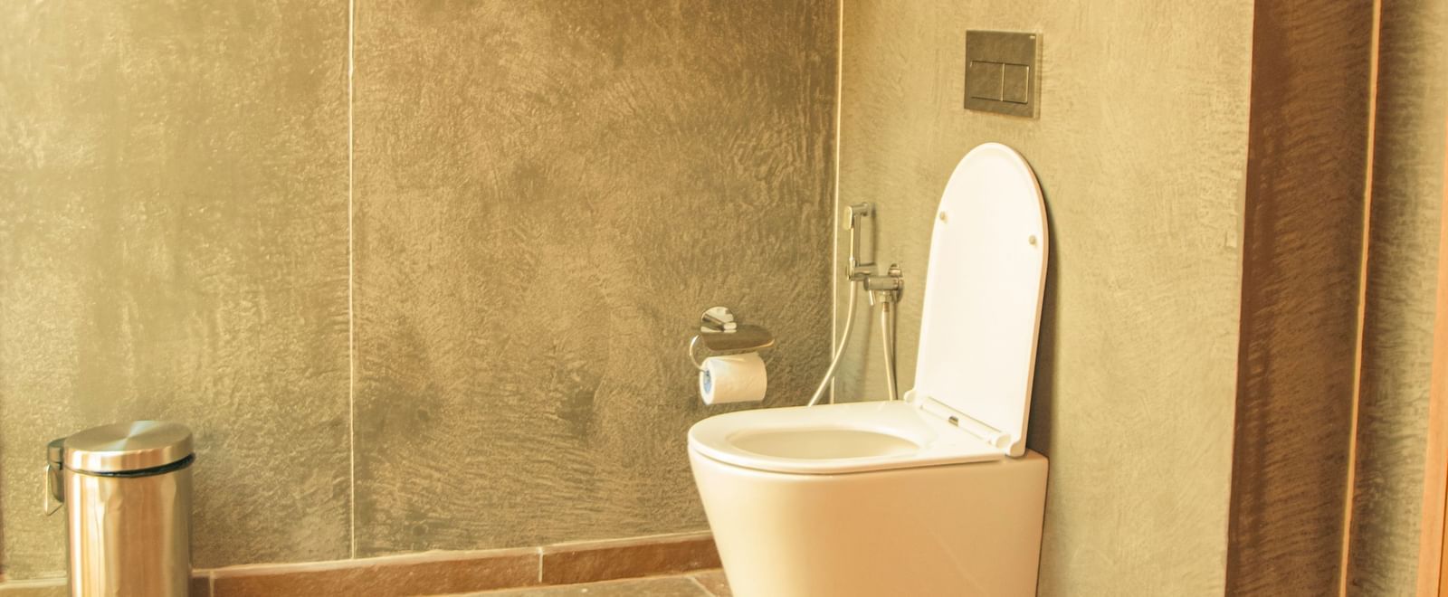 Bathroom with grey walls, toilet and towels at Fireflies Resorts, Kabini.