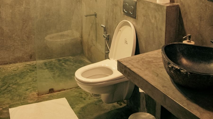 Bathroom with toilet, black basin, and overhead lighting at Fireflies Resorts, Kabini.