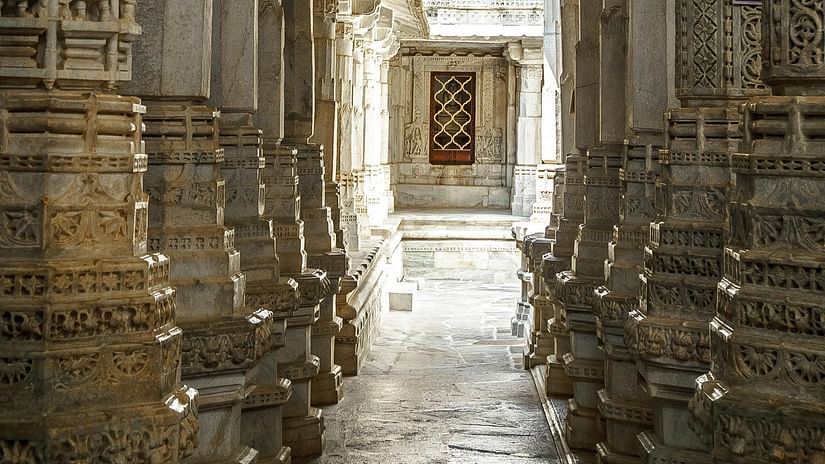 Intricately carved rock pillars lining a narrow temple corridor, showcasing detailed craftsmanship.