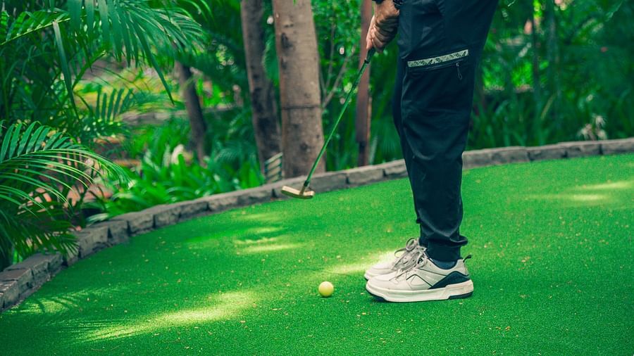 A man playing golf on a green course, wearing dark clothes at The Ananta Udaipur