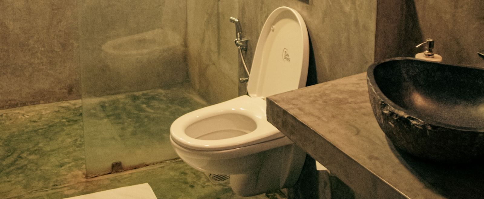 Bathroom with toilet, black basin, and overhead lighting at Fireflies Resorts, Kabini.