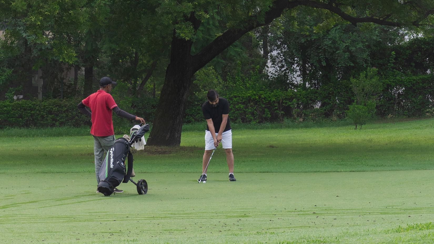 A golfer and his caddy at the golf course - Karma Lakelands.