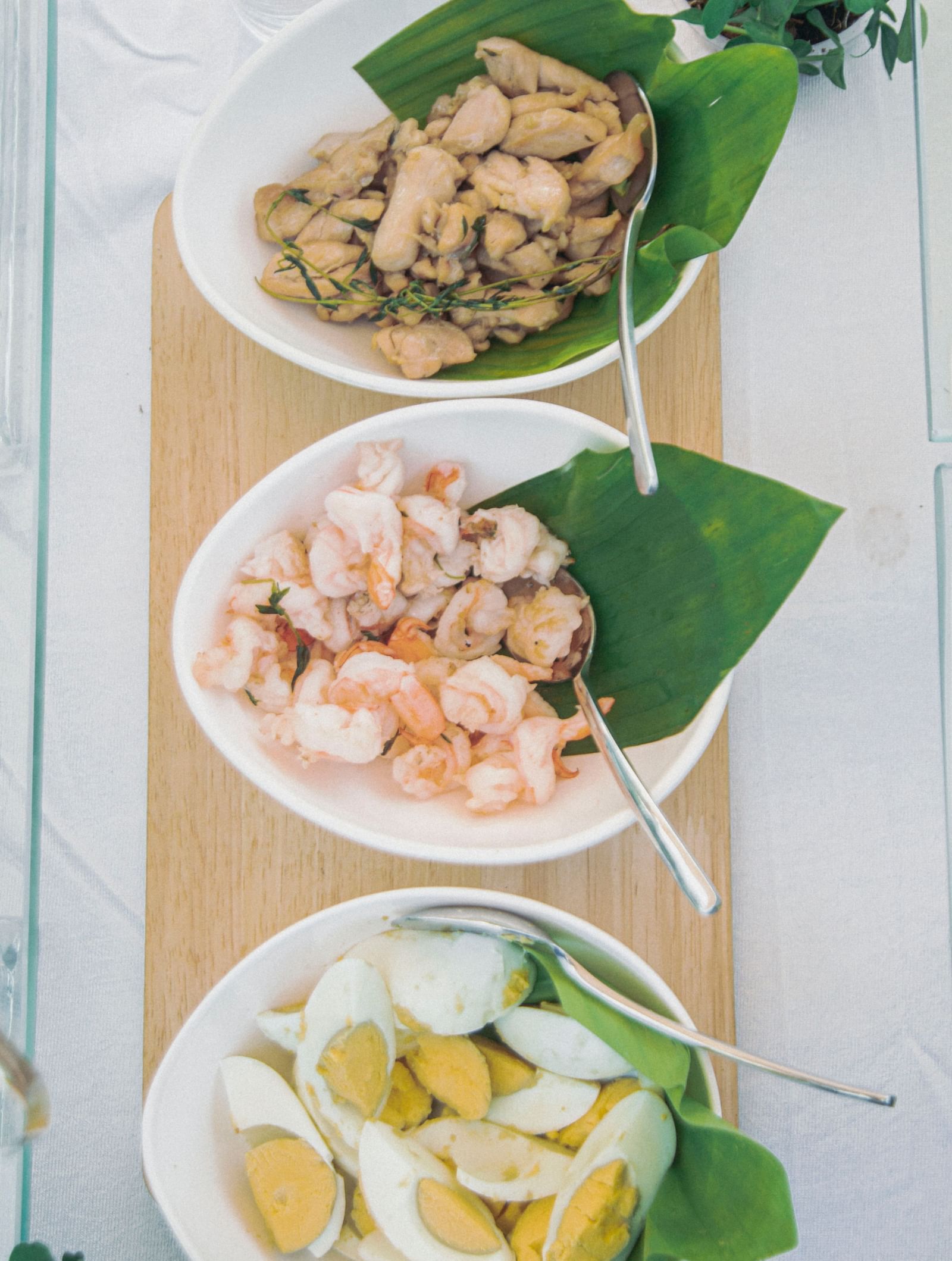 Vertical display of small bowls containing prawns, sliced boiled eggs, chicken cubes, and greens at Fireflies Resorts, Kabini.