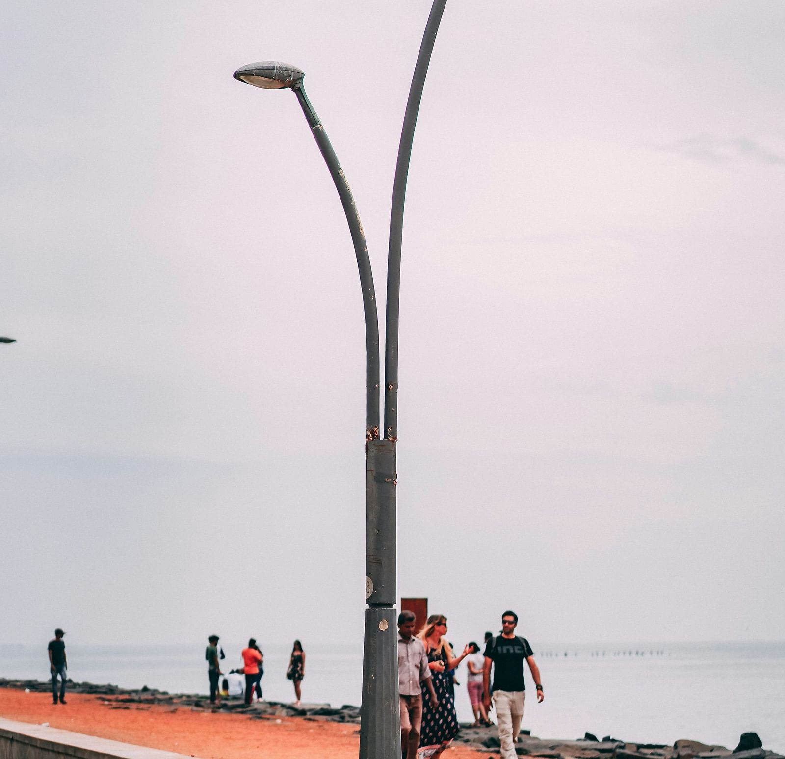 people walking next to the beach with a street light in view as well