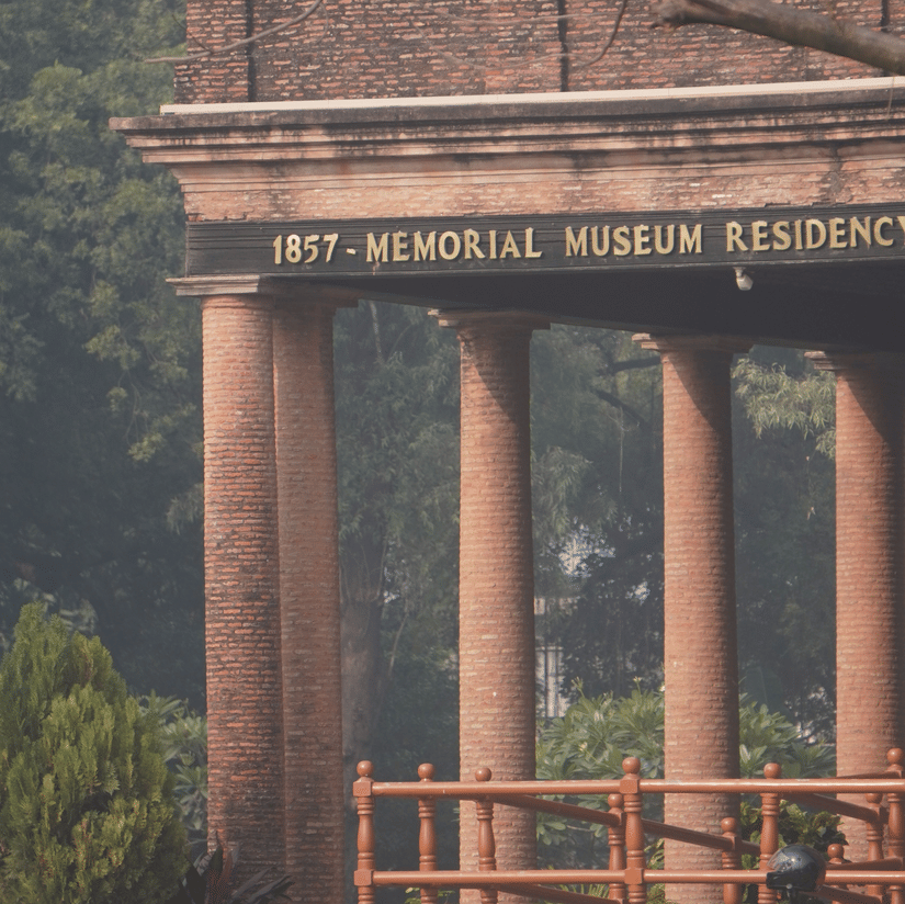 A partial view of the memorial museum with trees at the back. Four of the pillars are visible along with the railings that re guarding it. 
