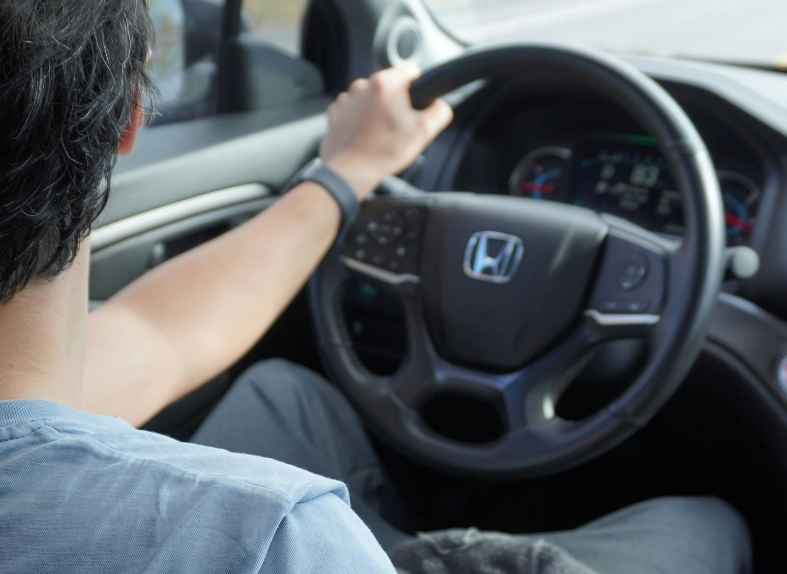 A man driving a car with his hands placed on the steering wheel.